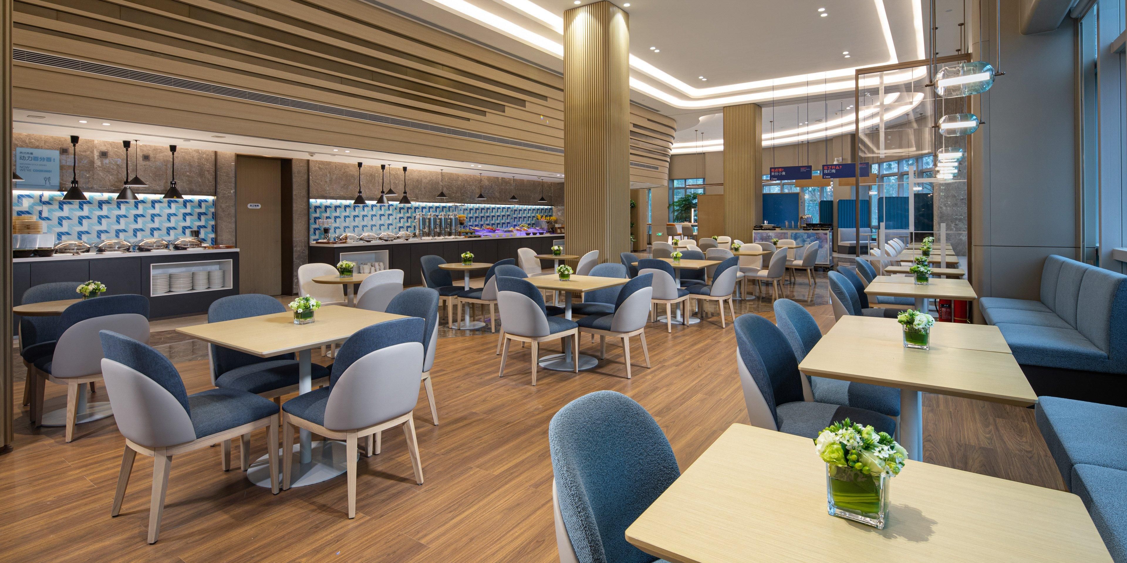 Een modern restaurant met diverse zitmogelijkheden, waaronder tafels, zitjes en een bar, met een toonbank waar eten gepresenteerd wordt.