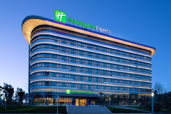 A Holiday Inn Express hotel with a curved facade, multiple floors, and a prominent green and white logo.