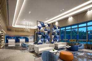 A modern hotel lobby with a reception desk, seating area, and large windows. - Holiday Inn Express Yibin (Yibin)