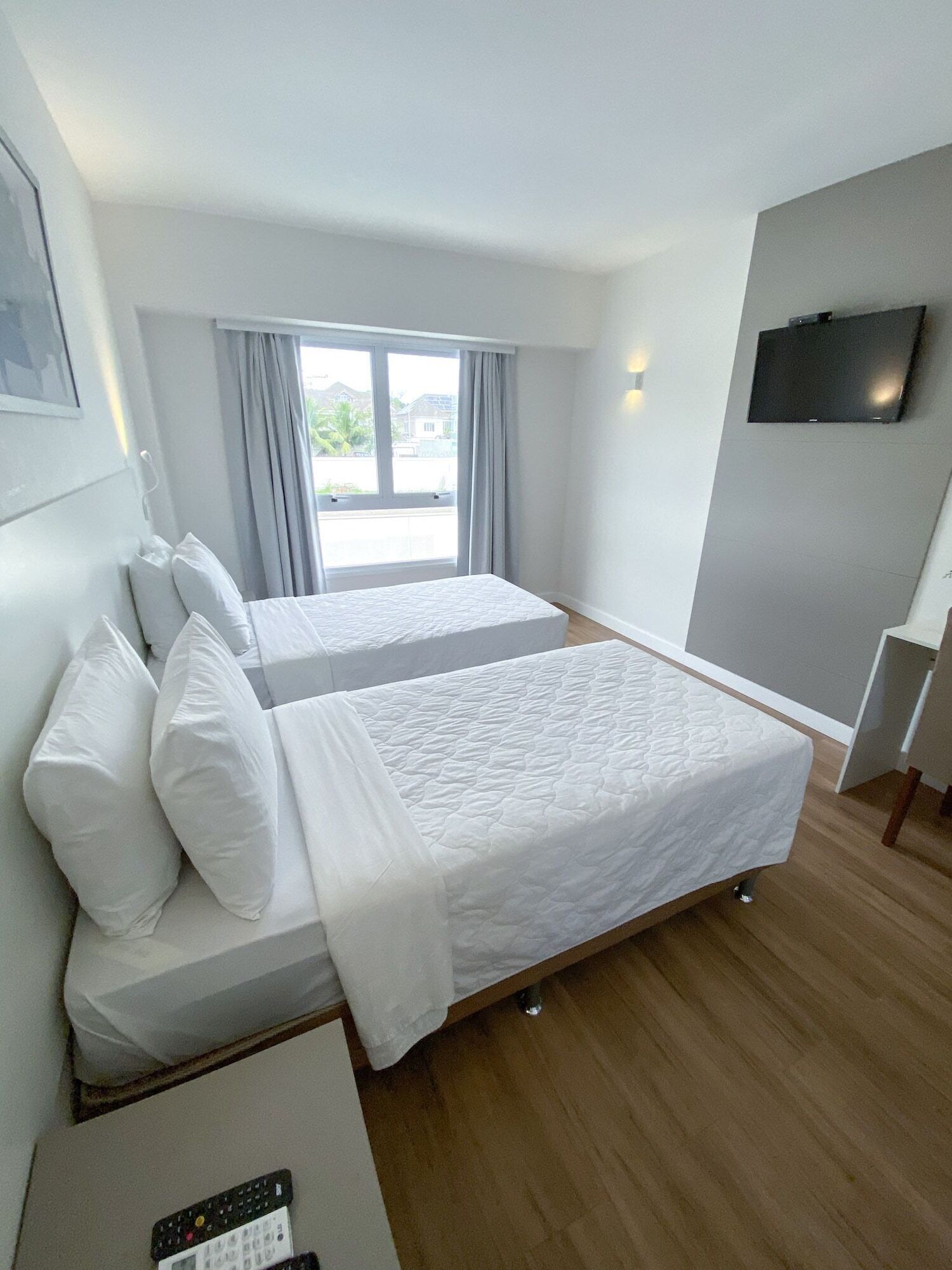 Habitación de hotel con dos camas, televisión y vista al exterior.