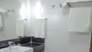 Ein Badezimmer mit weißem Waschbecken, schwarzer Arbeitsplatte, weißer Toilette und einem kleinen Mülleimer.