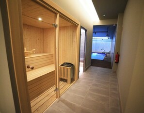A hallway leading to a sauna room with a wooden bench and a small trash bin. - Imi Hotel & Spa (Ourense)