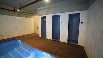 Una piscina con escalones de acceso, suelo de madera y paredes de azulejos.
