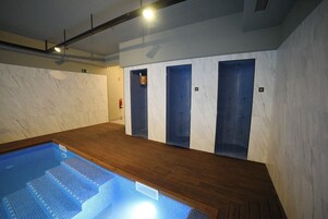 Una piscina con escalones de acceso, suelo de madera y paredes de azulejos.