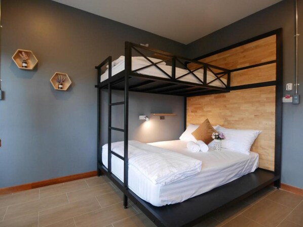 A bunk bed room with a wooden headboard, a small bedside table with a lamp, and two hexagonal wooden shelves on the wall. - Ray Hostel (Chiang Mai)