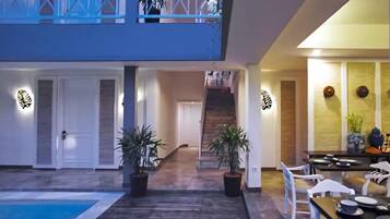 A spacious indoor area with a pool, a staircase, and a dining area with chairs and tables.