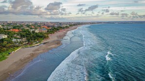 Vista aérea de una ciudad costera con playa, edificios y cielo despejado.