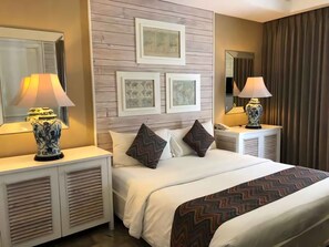 A hotel room with a bed, two nightstands, a mirror, and framed pictures on the wall. - The Kanjeng Suites Petitenget (Seminyak)