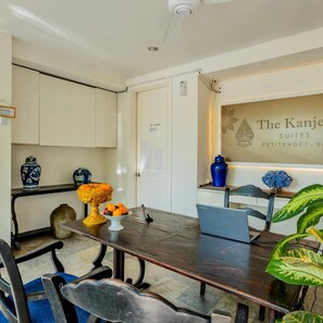 A dining area with a dark wooden table, chairs, and a decorative centerpiece. - The Kanjeng Suites Petitenget (Seminyak)