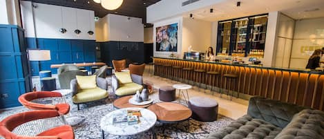 Un espace de détente moderne comprenant un bar, des coins salon et une grande œuvre d’art accrochée au mur.