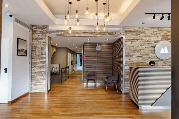 Un espace d’accueil moderne avec un mur en pierre, des lambris en bois et un comptoir d’accueil.