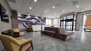 Tilava aula, jossa on modernit istuimet, suuri seinämaalaus ja lasinen sisäänkäynti.