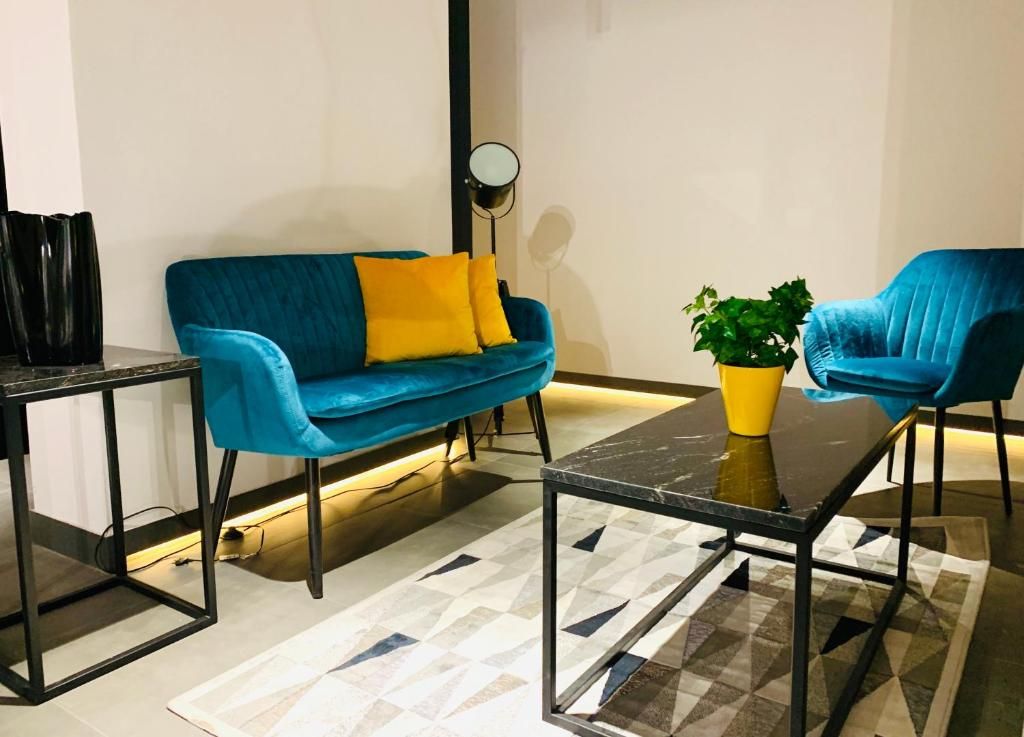 Uma sala de estar moderna com um sofá azul, uma poltrona combinando, uma mesinha e um vaso de planta.