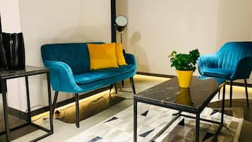 Uma sala de estar moderna com um sofá azul, uma poltrona combinando, uma mesinha e um vaso de planta.