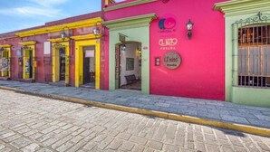 A row of colorful buildings with a prominent pink building featuring a sign for 'El Nino Posada' and a 'Hotel' sign. - Capital O El Nito Posada (Oaxaca)