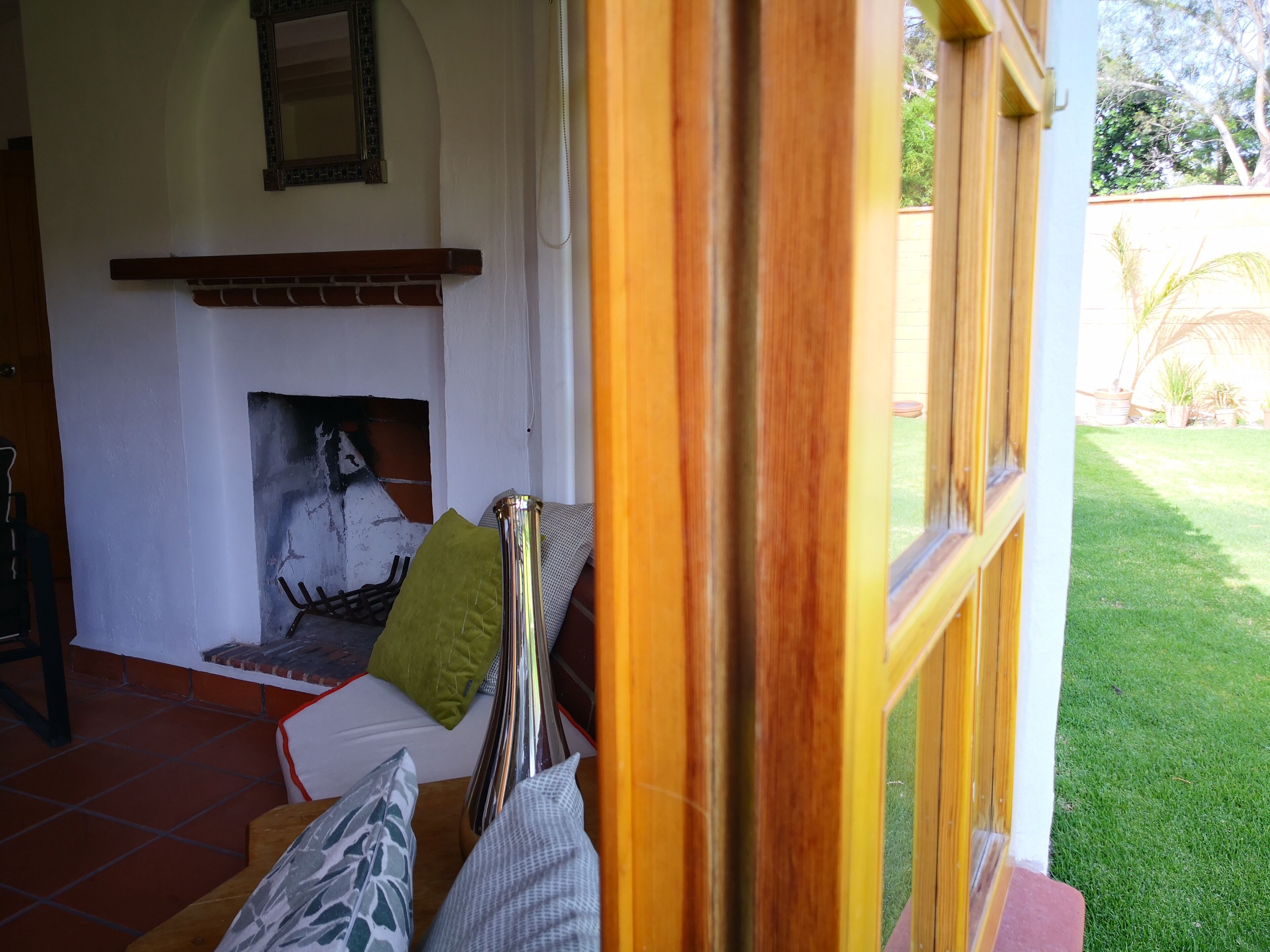 Una sala de estar acogedora con chimenea, un sofá y una ventana con vistas a un jardín.