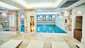 Ein geräumiger, überdachter Pool mit freiem Blick, umgeben von Backsteinwänden und Steinböden.