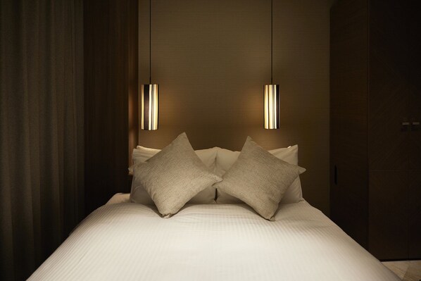 A neatly made bed with two pillows, a dark curtain on the left, and two pendant lights hanging above. - Alfit Hotel & BAR Akasaka (Tokyo)