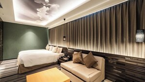 Ein modernes Hotelzimmer mit einem Bett, einer Couch, einem Couchtisch und einer Decke mit Wolkenmuster.