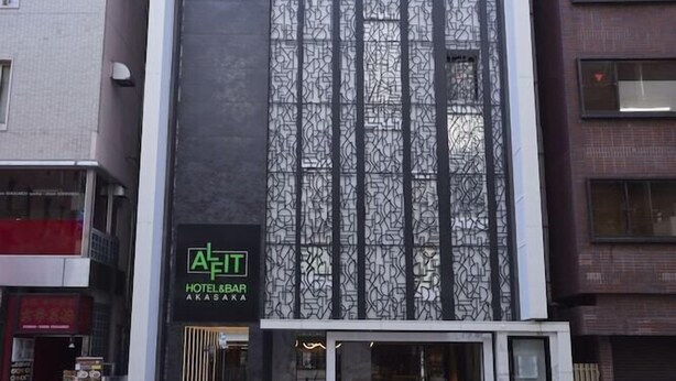 Ein modernes Hotel mit großer Glasfassade, einem gut sichtbaren Schild für 'AFIT HOTEL & BAR AKASAKA' und einem sauberen, städtischen Straßenbild.
