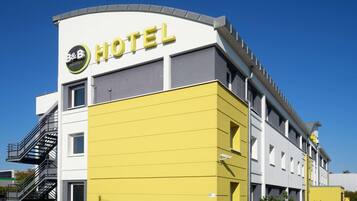 Um edifício de hotel moderno com fachada amarela e uma placa com a inscrição "B&B HOTELS".