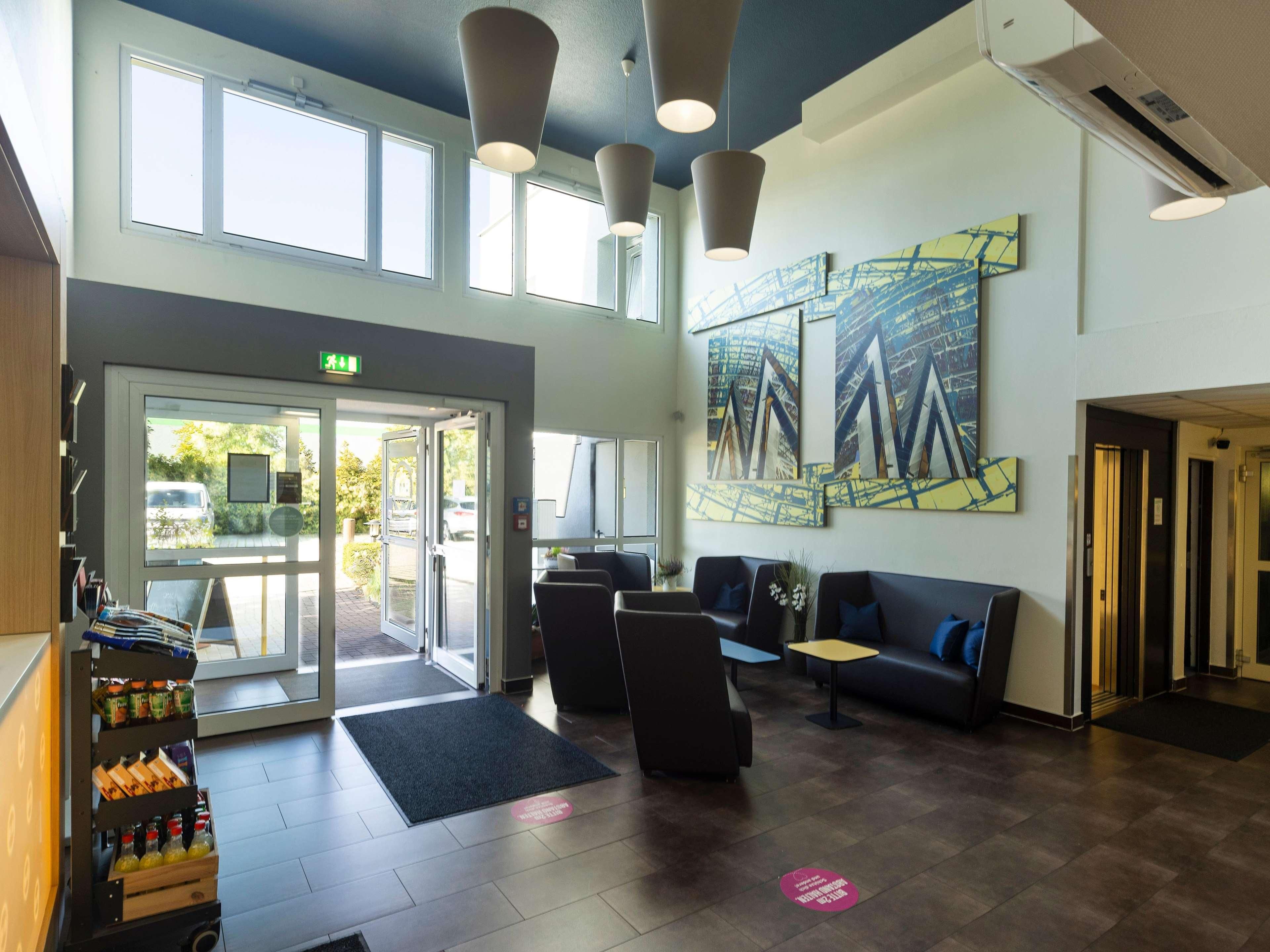 A modern lobby with a reception desk, seating area, and artwork on the walls.