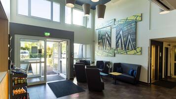 A modern lobby with a reception desk, seating area, and artwork on the walls.
