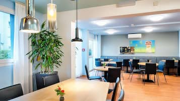 Un comedor moderno con una mesa de madera, sillas negras e iluminación colgante.