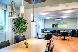 A modern dining area with a wooden table, black chairs, and pendant lighting. - B&B Hotel Köln-frechen (Frechen)