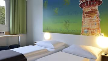 Een hotelkamer met twee bedden, een bureau met een lamp, een raam met gordijnen en een muur met een muurschildering van een vuurtoren.