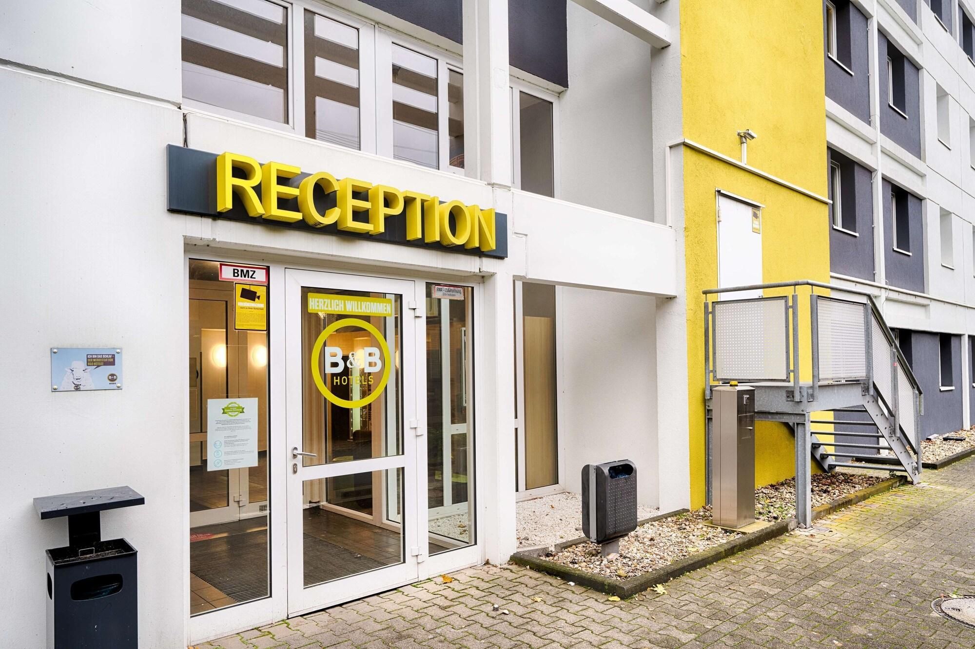 A hotel reception with a glass door, a sign reading "RECEPTION", and a yellow wall.