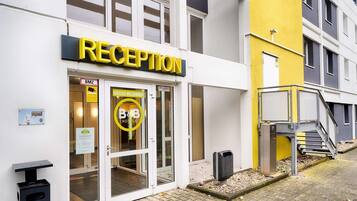 A hotel reception with a glass door, a sign reading "RECEPTION", and a yellow wall.