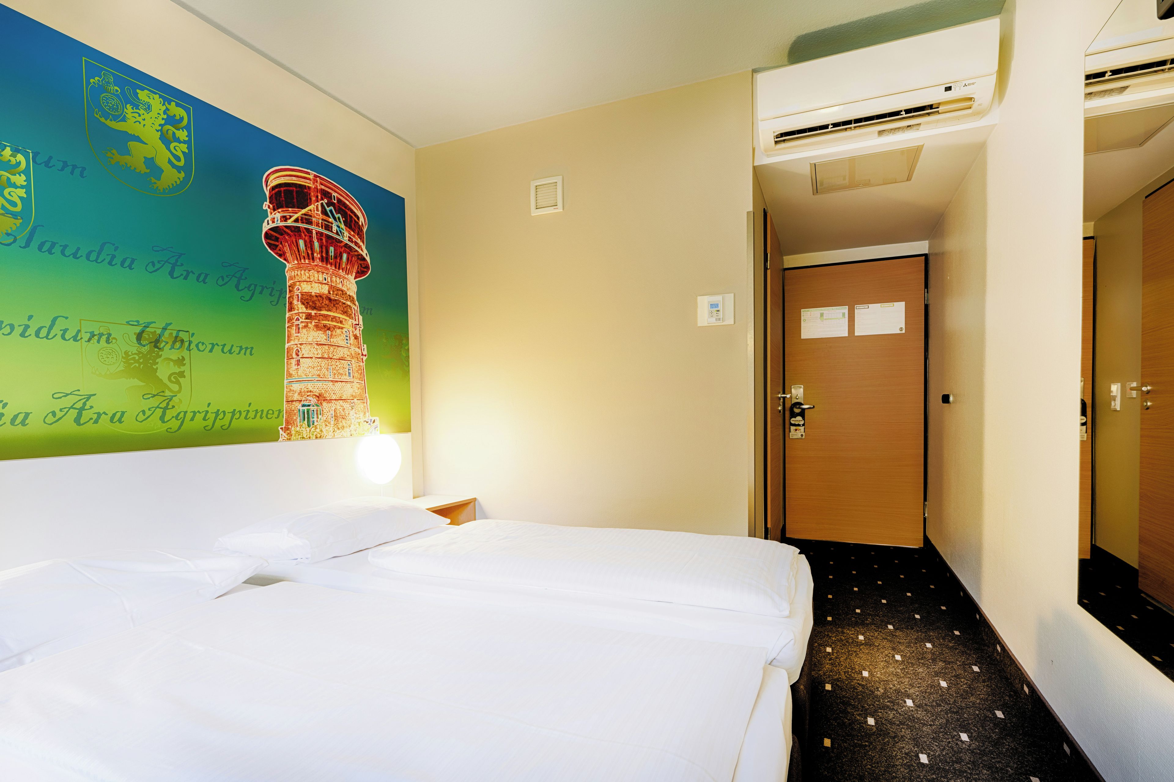 Een hotelkamer met een bed, een wandairconditioner, een deur en een gang.
