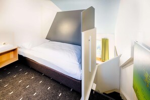 A compact hotel room with a bed, a small desk, and a chair. - B&B Hotel Köln-frechen (Frechen)