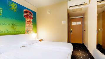 Ein Hotelzimmer mit Bett, Wand mit Wandmalerei, Klimaanlage und Tür.