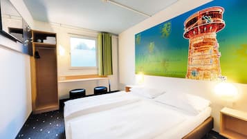 Habitación de hotel con cama, ventana, armario y un mural de una torre.