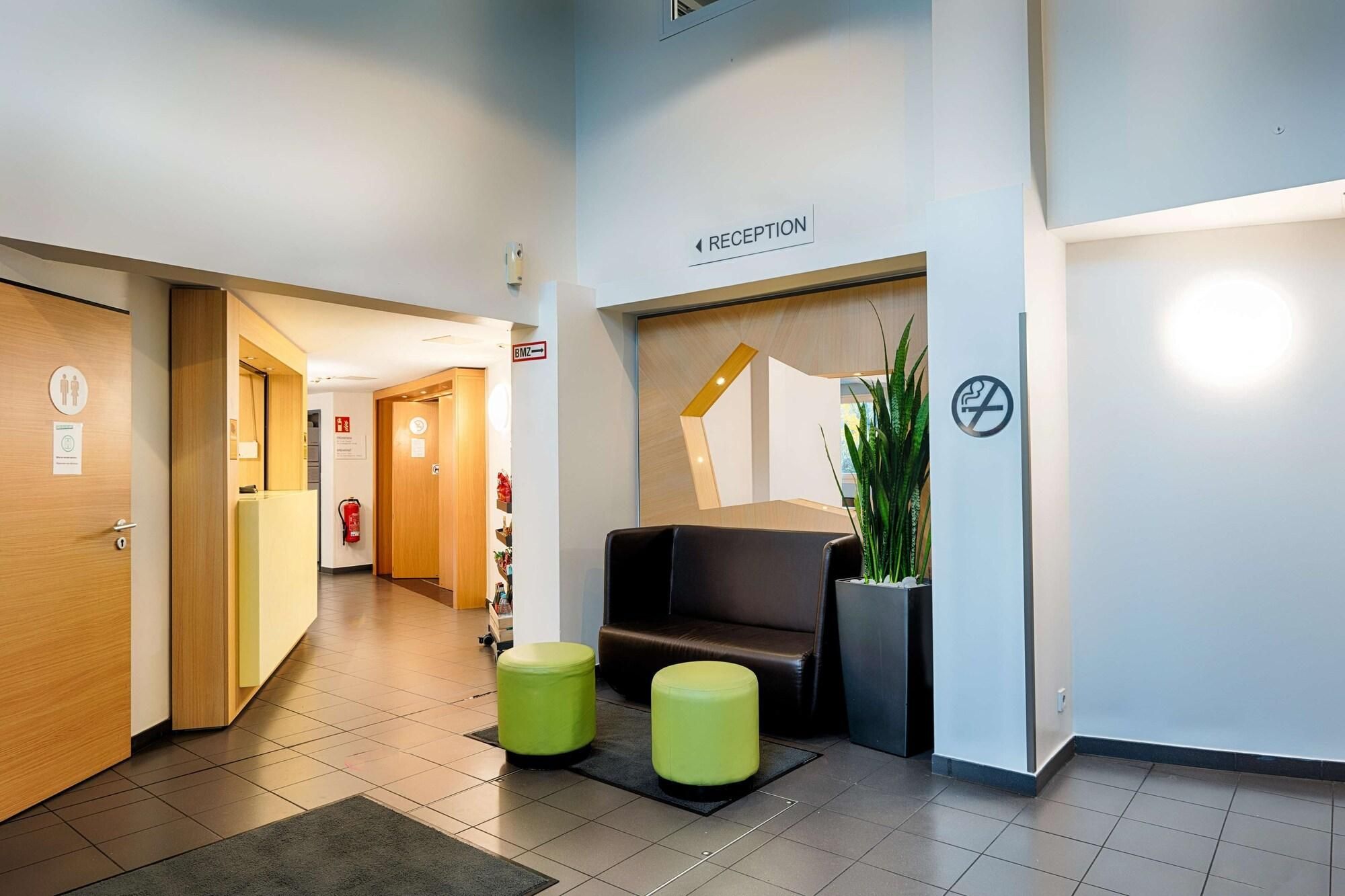 A reception area with a reception desk, a sign indicating the reception, a fire extinguisher, and a no-smoking sign.