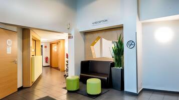 A reception area with a reception desk, a sign indicating the reception, a fire extinguisher, and a no-smoking sign.