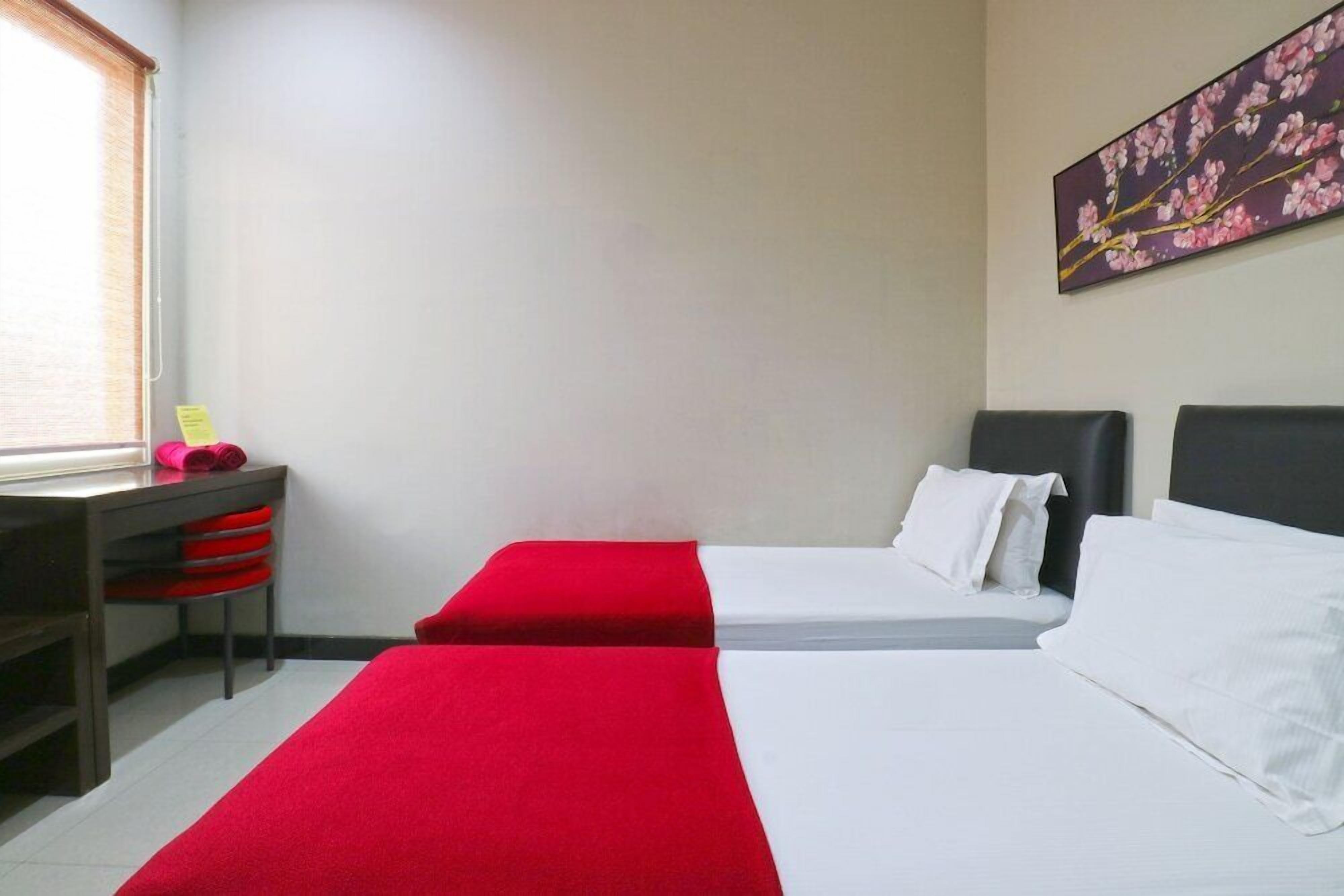 A hotel room with two beds, a desk with a chair, and a window.