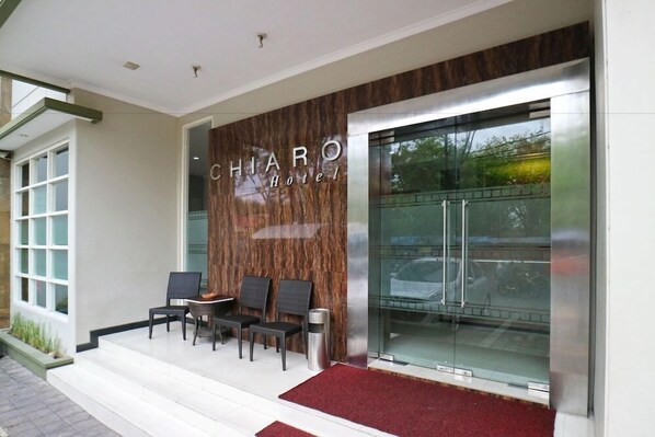 Exterior del Hotel CHIARO con fachada moderna, entrada de vidrio y una alfombra roja que conduce a la entrada.