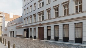 A building with a row of windows, a brown door, and a cobblestone street. - Hotel Cube (Prague)