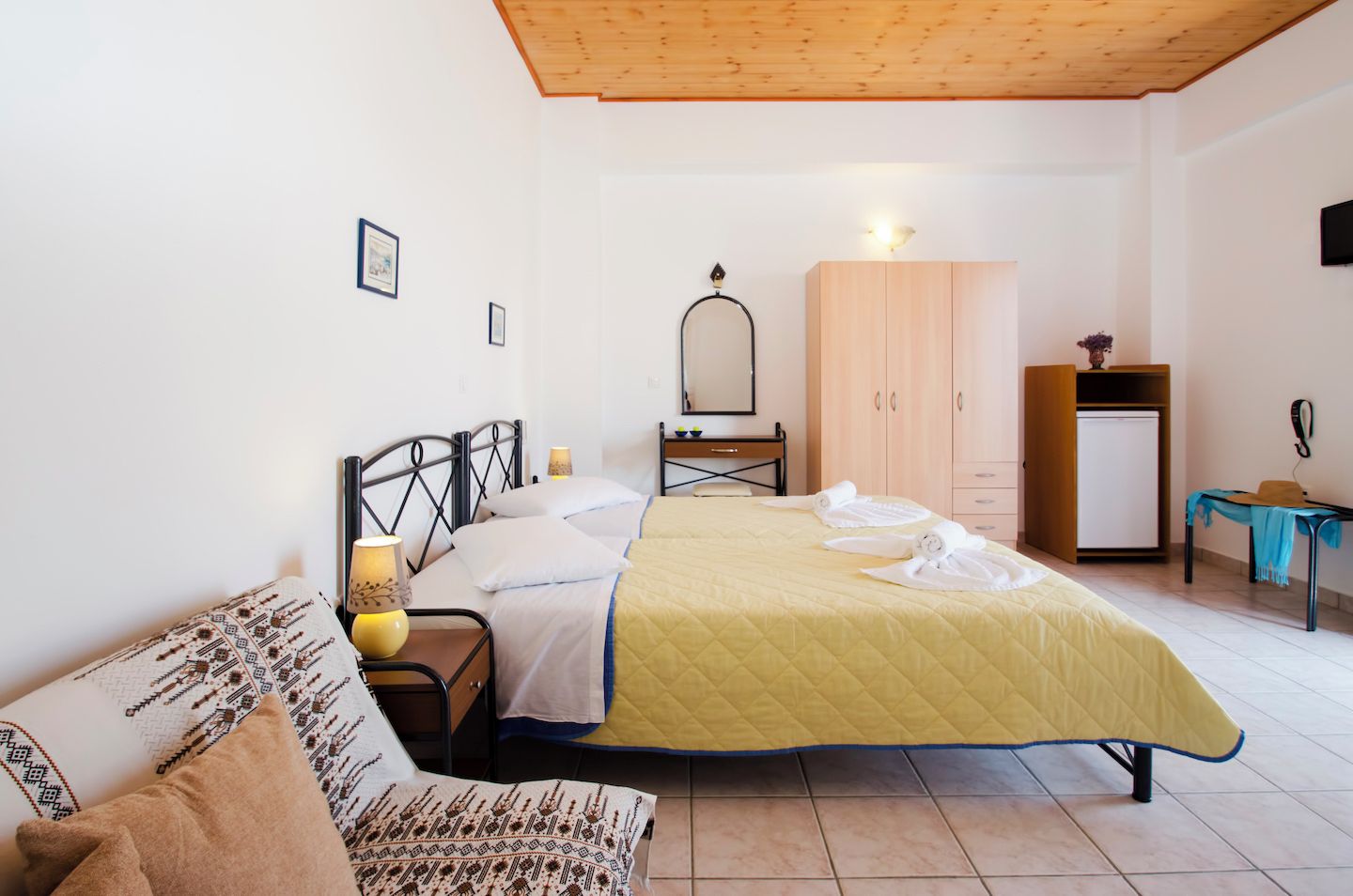 A bedroom with a bed, bedside table, lamp, wardrobe, and a desk with a chair.