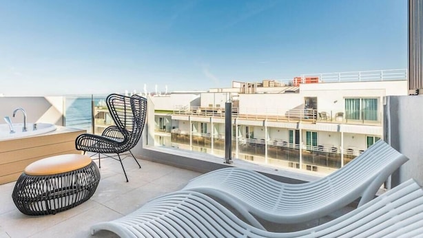A rooftop terrace with a pool, lounge chairs, and a bar area.