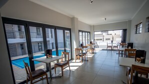 A spacious dining area with large windows, a pool view, and multiple tables and chairs. - Innov8 Spaces (Johannesburg)