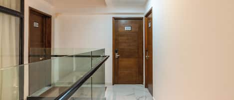 A hallway with a glass railing, wooden doors numbered 104 and 105, and a tiled floor.