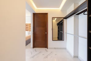 Un pasillo con una puerta de madera, un espejo y una cama con cabecera.