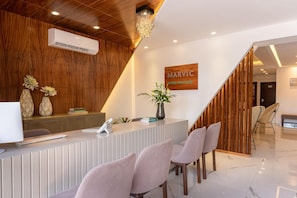 Zona de recepción de un hotel con un escritorio de madera, una araña y un cartel que dice 'MARVIC HOTEL BOUTIQUE'.