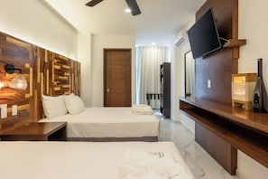 Habitación de hotel con dos camas, un televisor montado en la pared, cabecero de madera y chimenea.