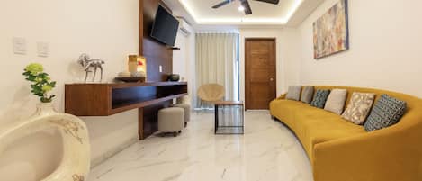 A modern living room with a curved sofa, a ceiling fan, a mounted TV, and a marble floor.