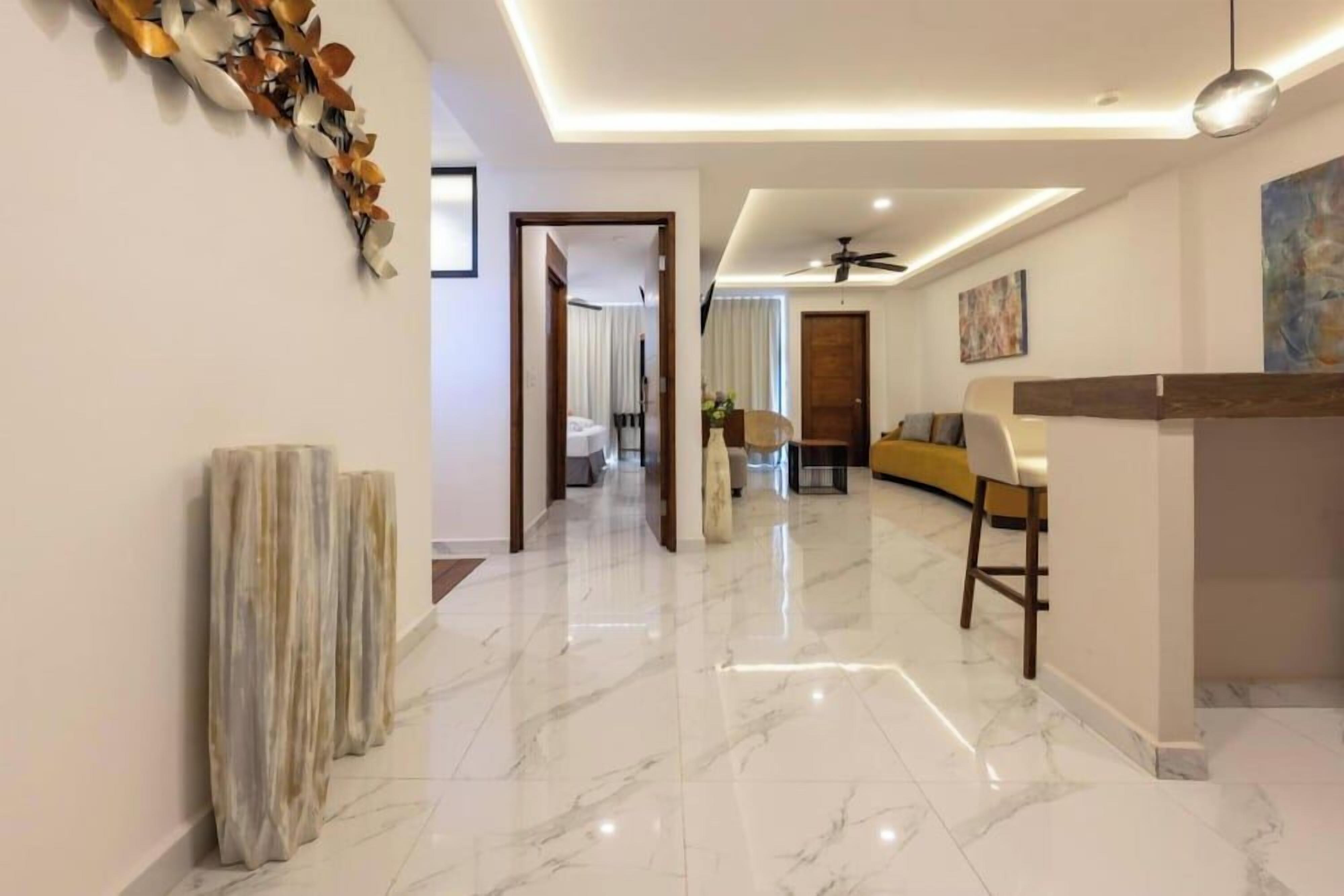 Un moderno hall de hotel con suelo de mármol, un mostrador de recepción, un sofá y un ventilador de techo.
